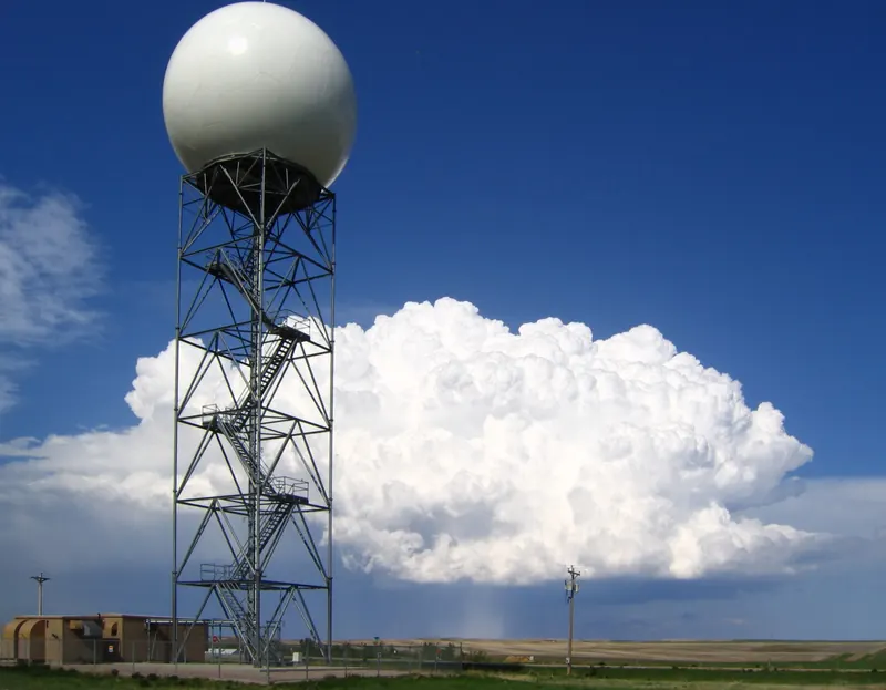 Un radôme de radar météorologique devant un nuage d’orage